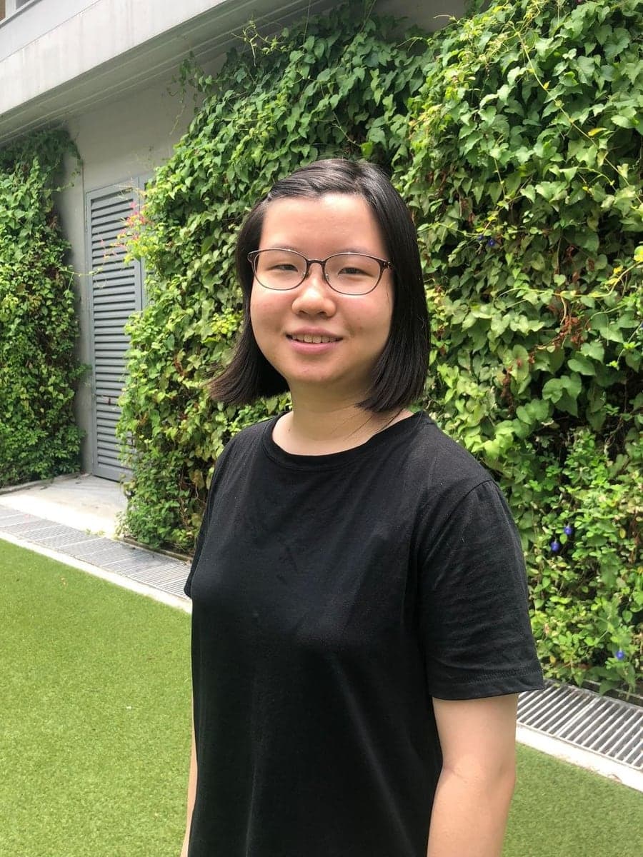 Chua Tse Hui in front of a wall of climbing plants at the edge of a lawn