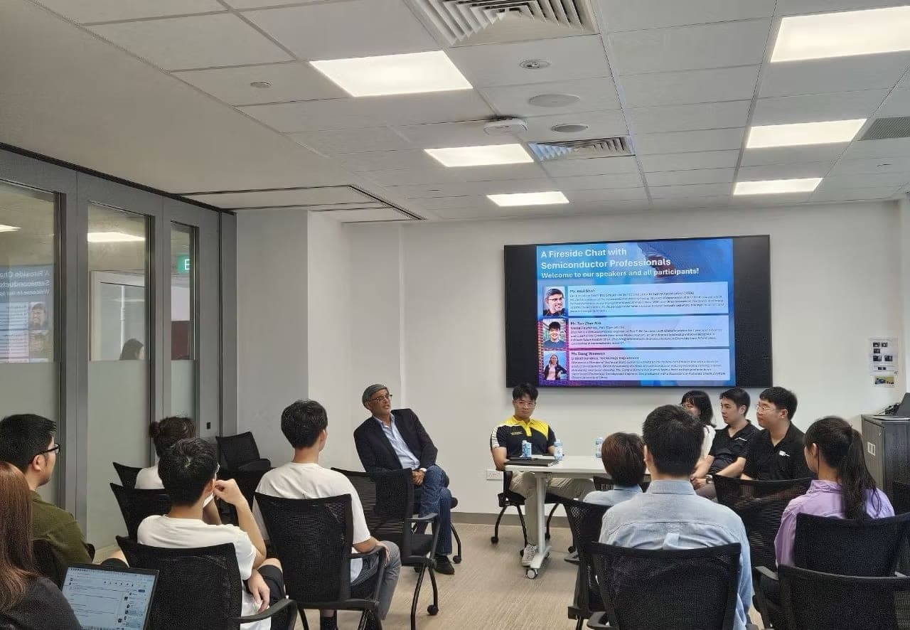 Speakers at a fireside chat with semiconductor professionals, seated in front of club members